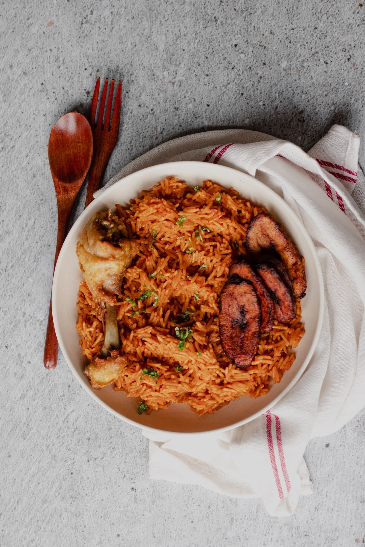 A GrubNmore jollof rice, chicken, and fried plantain plate, ready for delivery